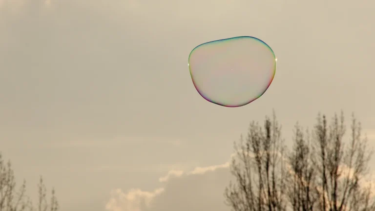 Sunlight on a soap bubble floating against a pale sky
